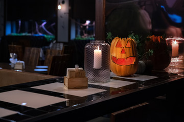 A pumpkin in the form of a smiling face is standing on the bar on the eve of the helloween holiday