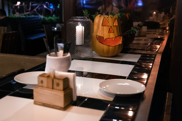 A pumpkin in the form of a smiling face is standing on the bar on the eve of the helloween holiday