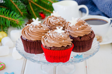 Chocolate cupcakes with cheese chocolate cream with a cup of coffee and marshmallows  for Christmas and New Year on a white wooden background.