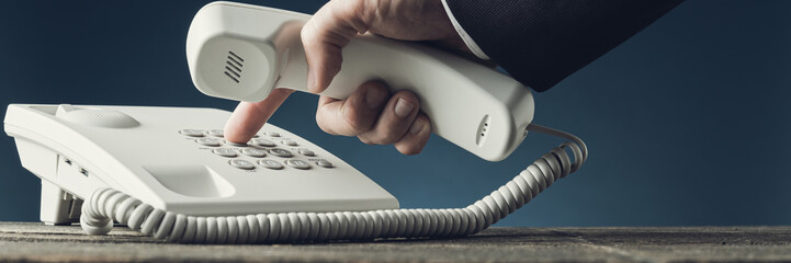 Wide view image of businessman dialing telephone number