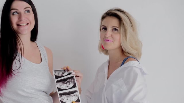 Mother and Pregnant Daughter Talking and Looking at Pictures of Ultrasound. Two Woman have Fun Chatting. Happy Family Have Joyfully Communication. Beautiful Women Look at Ultrasonic Images.