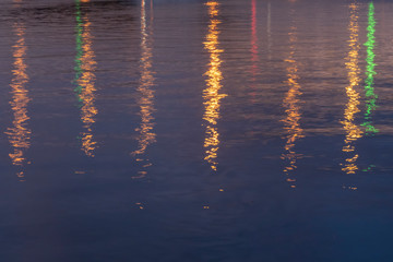 Blue or purple background with bridge lights reflection in river water at night. Soft focus.