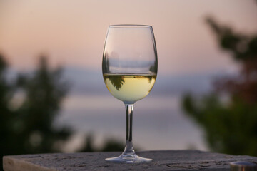 Obraz premium The glass of white wine and tropical sunset with sea