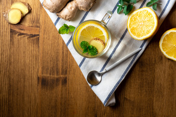 Hot winter drink. Ginger tea with lemon, honey and mint on a wooden background, top view, copy space. Herbal healing spicy tea