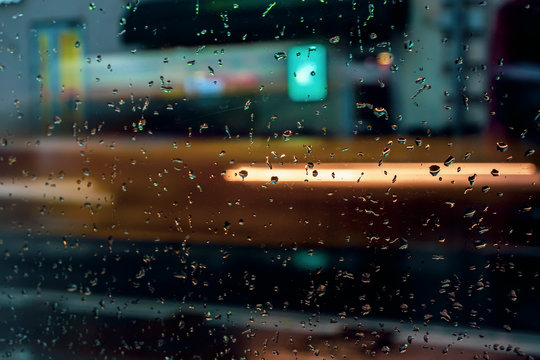 Abstract blurred colorful background. View through glass window with rain drops on bokeh city lights, night street scene © svetlanais