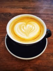 cup of latte with art on wooden table