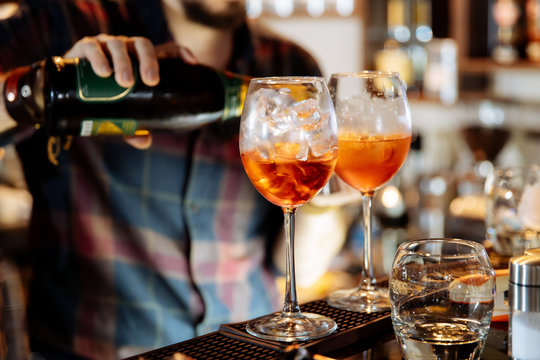 The barman pours Prosecco into the cocktail of Aperol Spritz