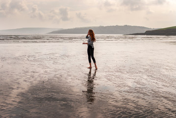 Young red-haired woman posing on the beach. Cloudy day.