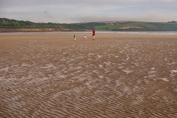 One man and a woman walking on sandy beach. One father and his daughter enjoying the day. family.