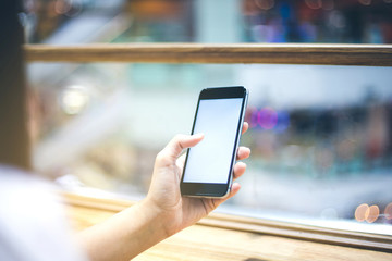 Mockup image of a woman's hand using black mobile phone or smartphone, with the blank white screen.