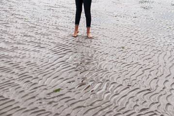 Woman walking on sandy beach leaving footprints in the beach.