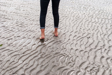 Obraz na płótnie Canvas Woman walking on sandy beach leaving footprints in the beach.