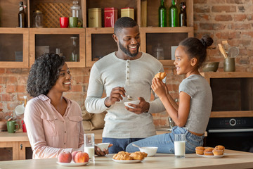 Positive black family having breakfast in beautiful kitchen