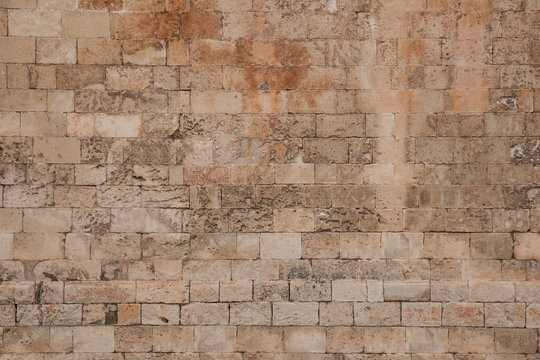 Old and weathered large stone blocks wall texture. Beige sandstone tones