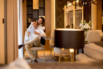 Young couple relaxing at luxurious home with digital tablet