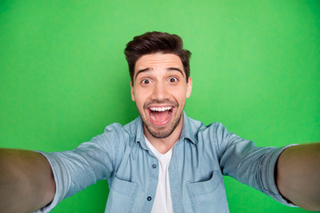 Self portrait of cheerful positive handsome man taking selfie having holidays on vacation relax fun isolated over green color vivid background