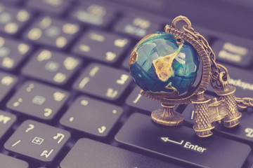 Worldwide communication, local link global reach concept : World globe, binocular on a laptop computer keyboard, depicts modern technology in communication shorten the way we connect and communicate
