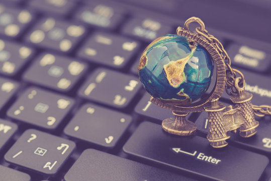 Worldwide communication, local link global reach concept : World globe, binocular on a laptop computer keyboard, depicts modern technology in communication shorten the way we connect and communicate