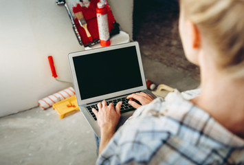 Cropped view of Young girl designer with laptop works in the repair place in the house. Choosing...