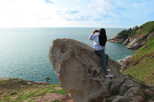Woman sitting and take photo of the Andaman sea at Krating cape Phuket Thailand