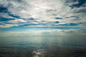 Bright beautiful seascape, sandy beach, clouds reflected in the water, natural minimalistic background and texture, sun behind, evening