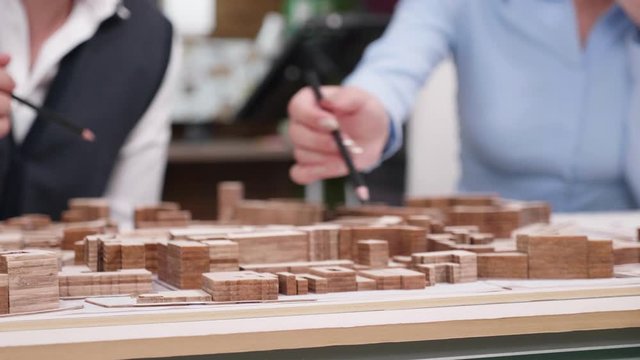 Close up of architects holding over miniature town