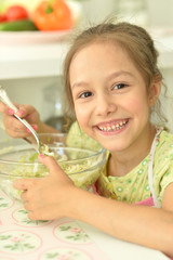 Portrait of cute girl eating salad on kitchen