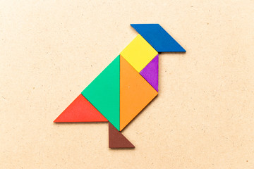 Color tangram puzzle in  shape on wood background