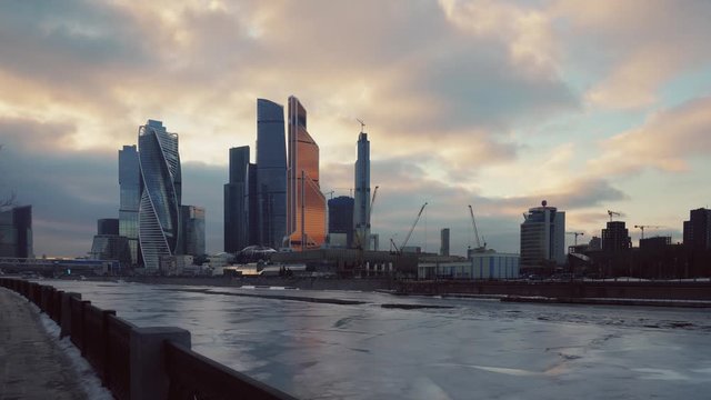 Financial District, Moscow City. Futuristic glass skyscrapers. Winter. Promenade is covered in snow. The water in the river froze turned into ice. Smooth slide the frame forward using steadicam. 4K