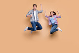 Full length photo of two people crazy lady guy jumping high celebrating best win raising fists excited wear casual plaid jeans clothes isolated beige background