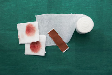 plaster,blood gauze and roll gauze on green surgical dress for clean wound