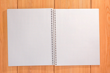 Open notebook paper with blank pages on wooden desk.