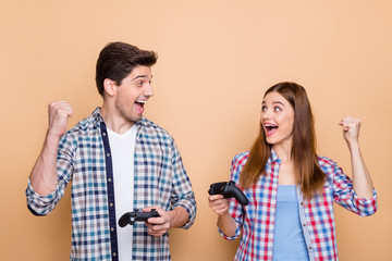 Photo of white cheerful positive beautiful stylish trendy couple of two people playing playstation with joysticks having won game playing in team isolated beige pastel color background