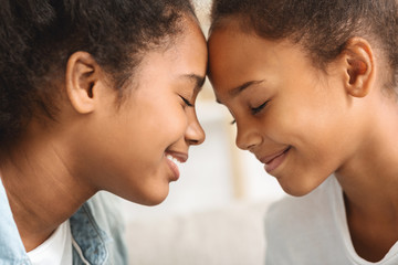 Two girls with eyes closed touching each other with foreheads