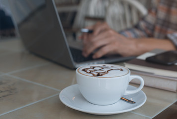 Man working on laptop computer and smartphone at cafe