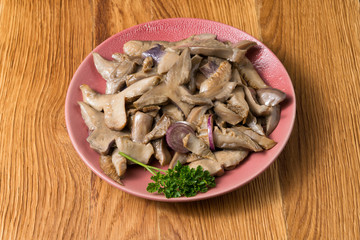 Fried mushrooms on a lilac plate stands on a beautiful wooden background