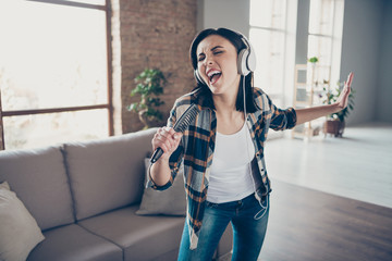 Fototapeta premium Photo of pretty lady rejoicing listening favorite melody in modern earflaps dancing and singing in hair brush concert preparation wear casual clothes apartment indoors