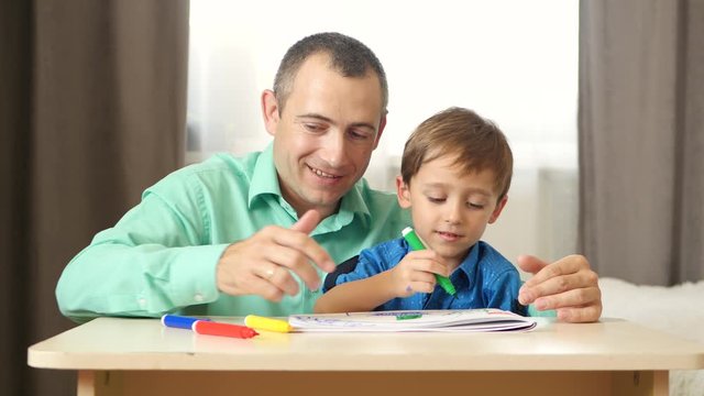 Dad and son spend time painting with colored felt pen. The concept of a happy family.