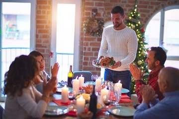 Beautiful family smiling happy and confident. Showing roasted turkey and applauding celebrating Christmas at home