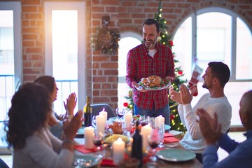 Beautiful family smiling happy and confident. Showing roasted turkey and applauding celebrating Christmas at home
