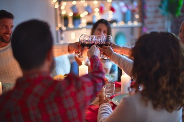 Beautiful family smiling happy and confident. Eating roasted turkey and toasting with cup of wine celebrating Christmas at home