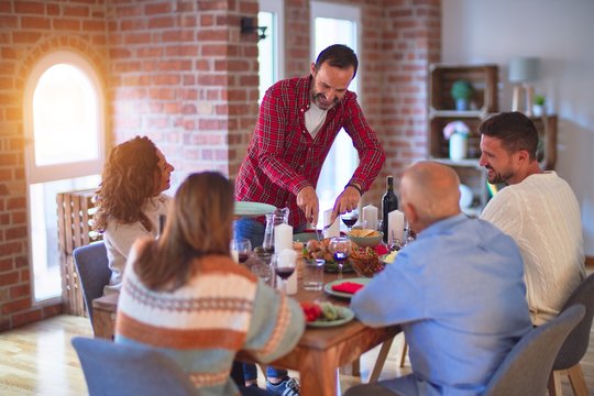 Beautiful family smiling happy and confident. Carving roasted turkey celebrating Thanksgiving Day at home