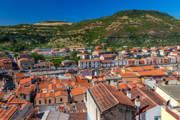 Panoramic view of Olbia, Sardinia, Italy. Historic old buildings with red rooftiles. Hill and blue sky in background.