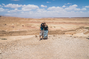 Two caucasian european white traveler girls standing on top of a cliff spreading arms over a desert land in Morocco