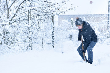 Fototapeta na wymiar Teenager removing snow with a shovel in the winter