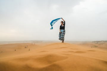 Obraz premium White traveler girl standing on a stormy sandy day in the Sahara Desert, in Morocco