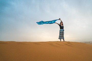 White traveler girl standing on a stormy sandy day in the Sahara Desert, in Morocco