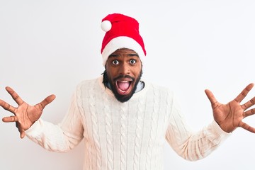 Young african american man wearing Christmas Santa hat over isolated white background celebrating crazy and amazed for success with arms raised and open eyes screaming excited. Winner concept