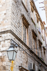 Stone house with lantern in narrow stone street in historic Dubrovnik city, Dalmatia, Croatia, blue sky with clouds, popular touristic destination 