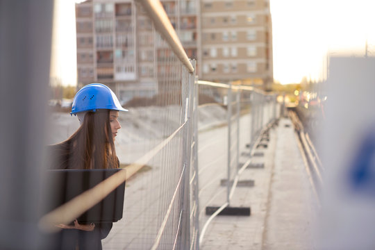 A beautiful young woman inspector checks the construction while holding a projector computer with her hands